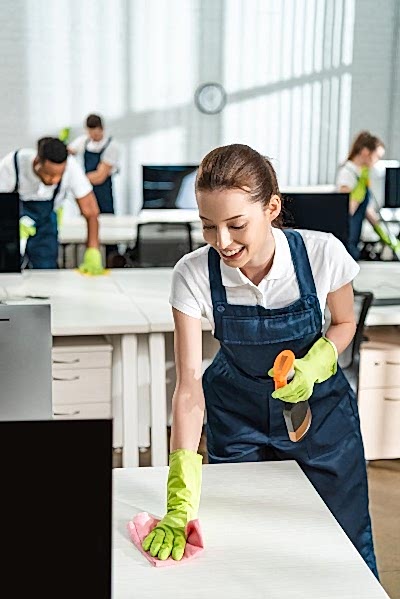 cheerful-cleaner-in-overalls-cleaning-office-desk-2022-12-16-17-52-49-utc empresa de limpieza de oficinas